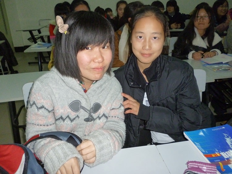 Two female Chinese students sitting together in classroom